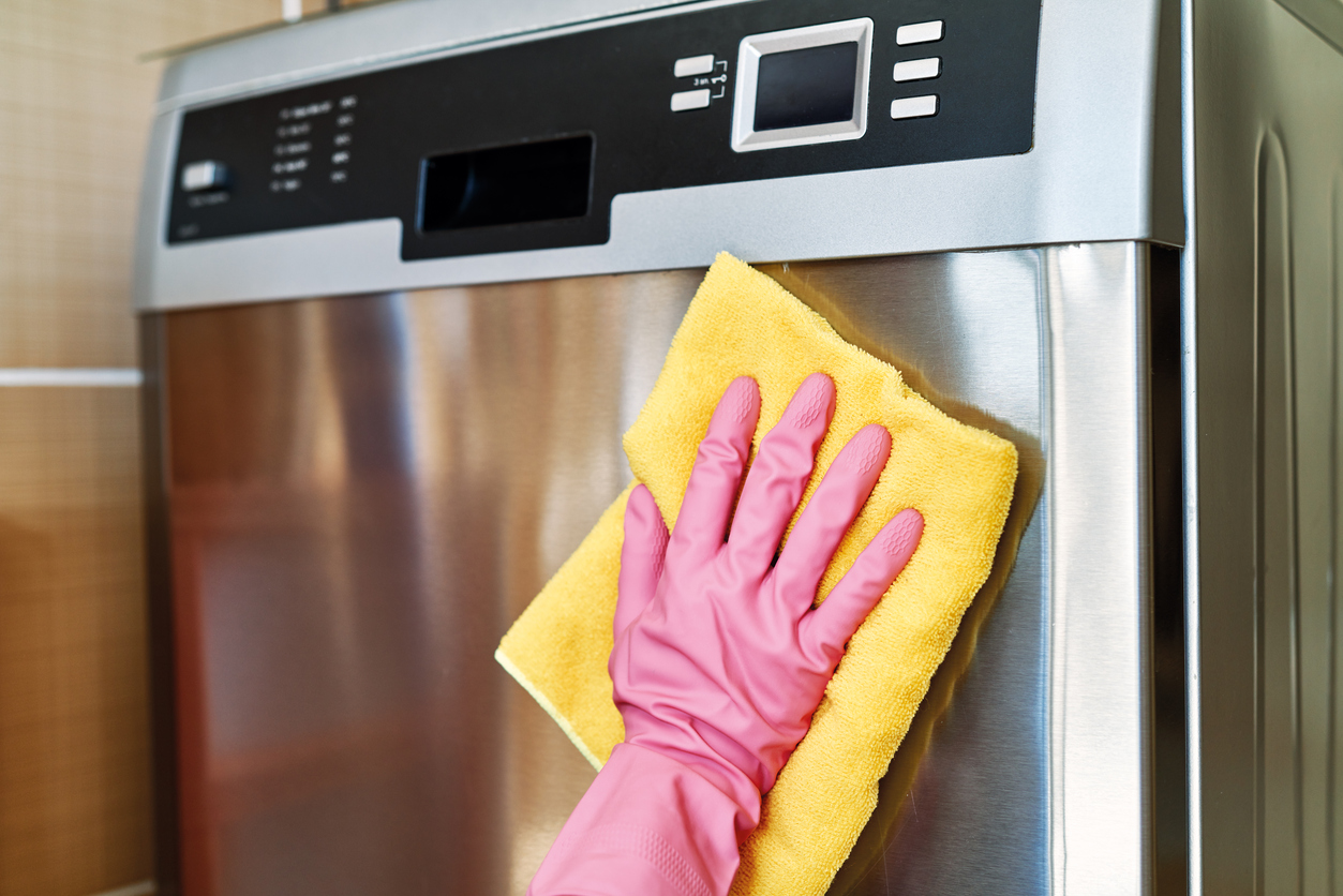 A woman using JAWS Glass Cleaner to wipe fingerprints on the dishwasher