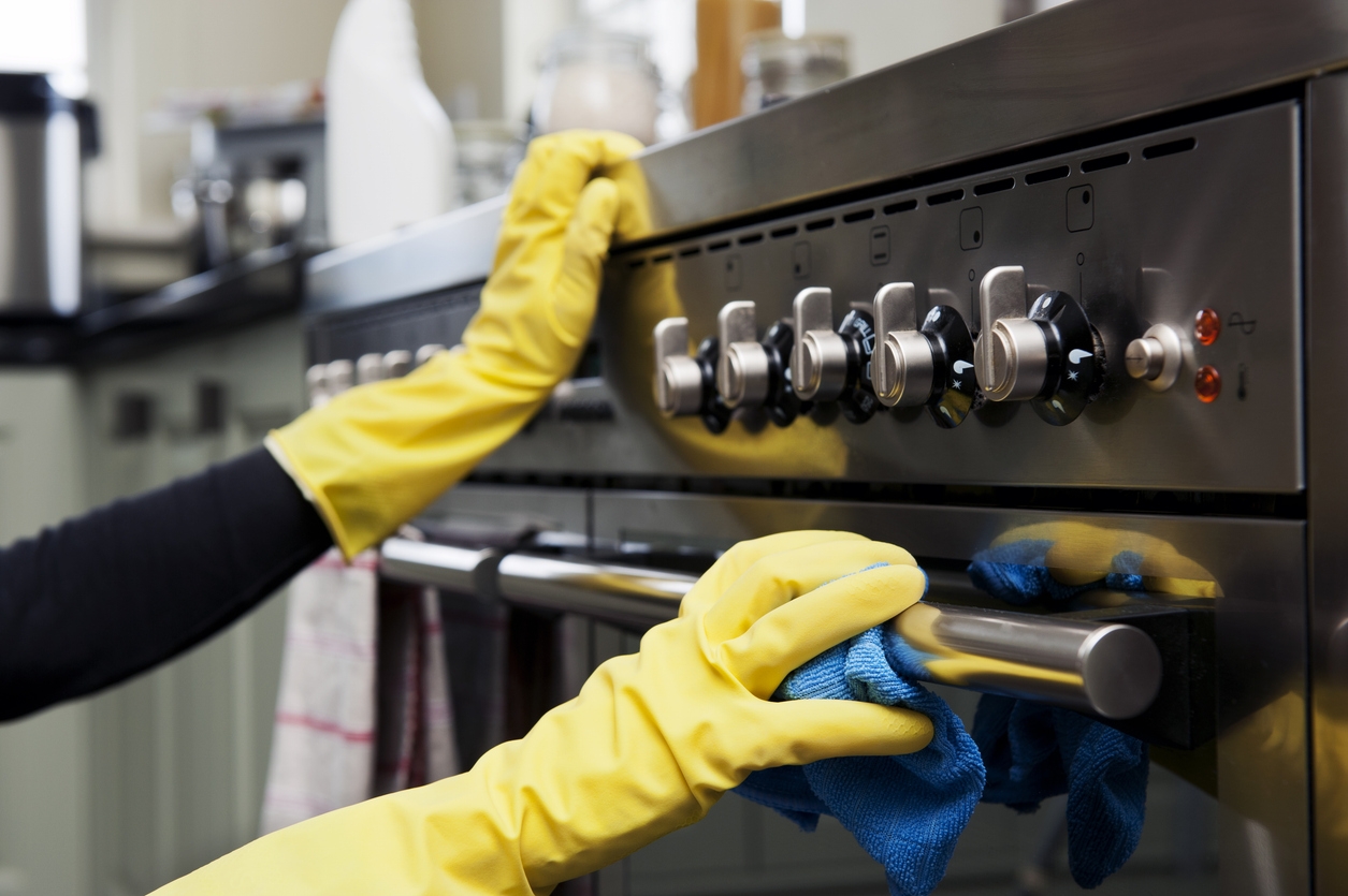 A woman cleaning stainless steel appliances using JAWS Kitchen Cleaner