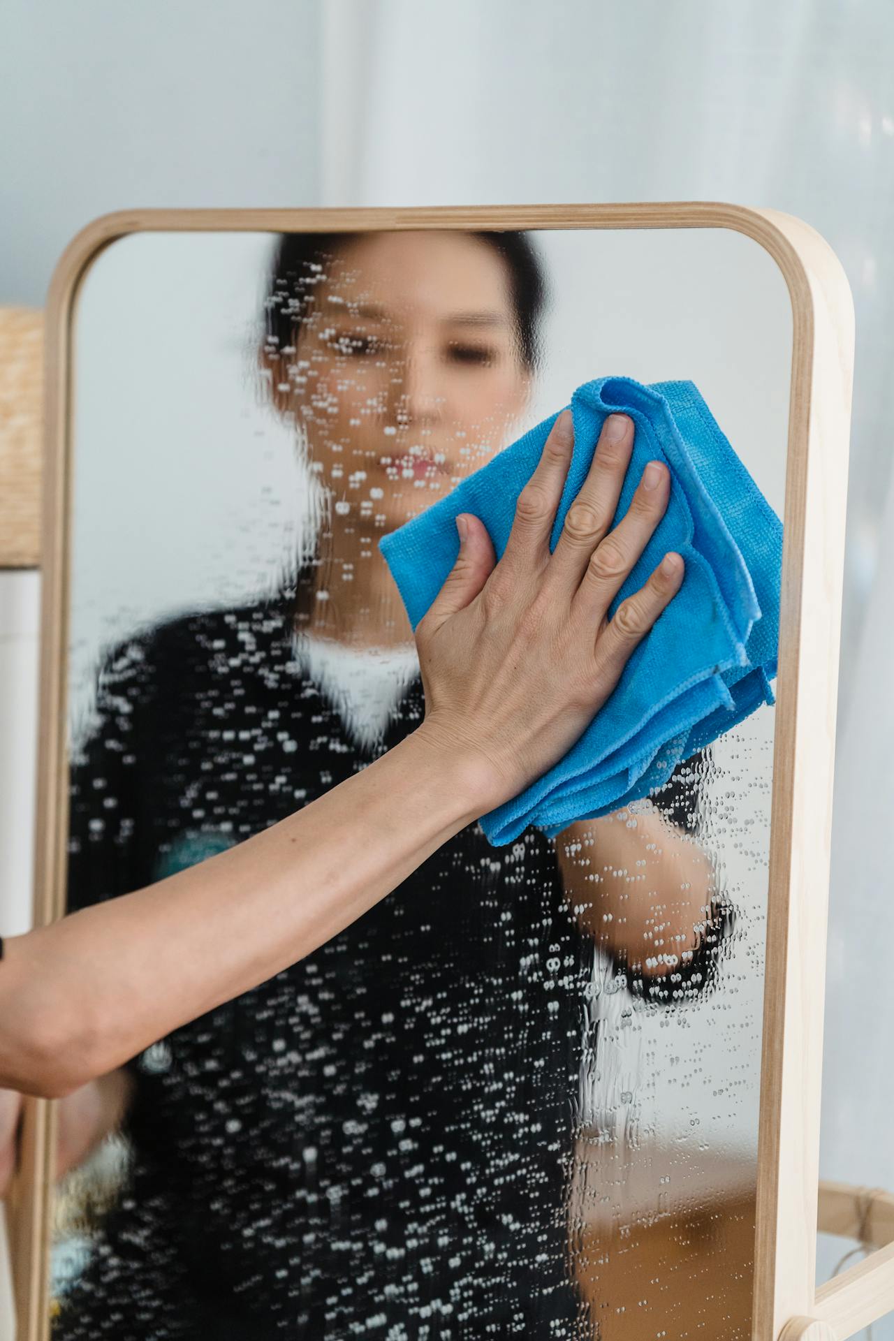 Cleaning a mirror by wiping it with a micro fiber cloth for a streak-free shine