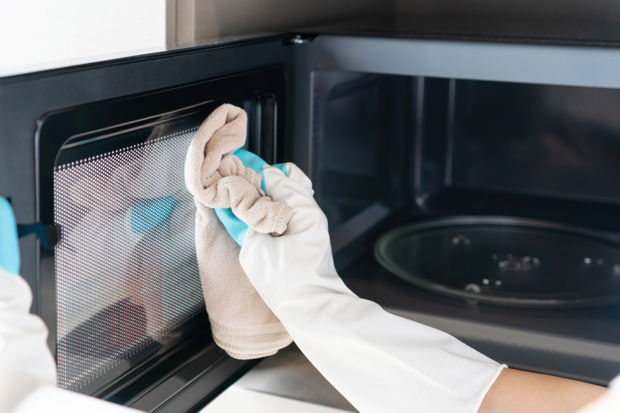 Woman cleaning inside of a microwave with Microfiber cloth