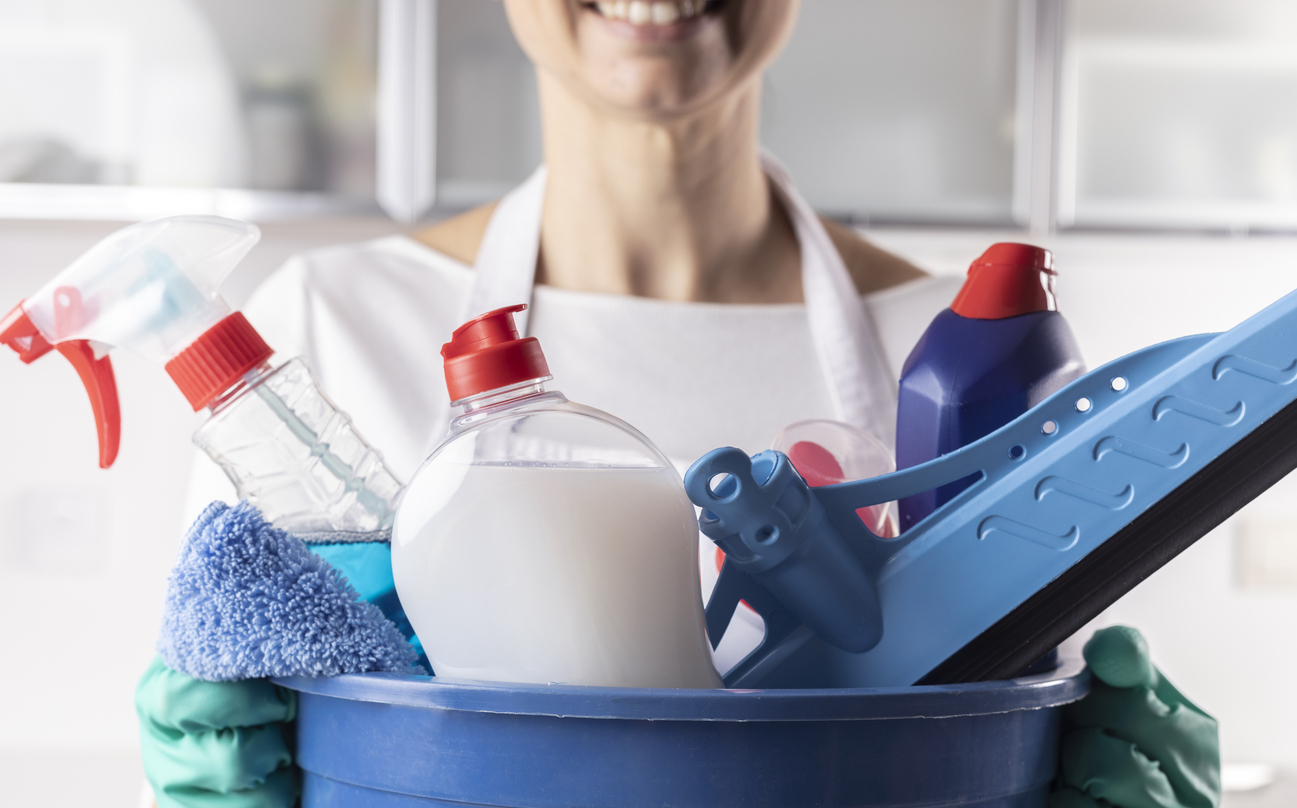 Woman holding a container of cleaning products in a bucket