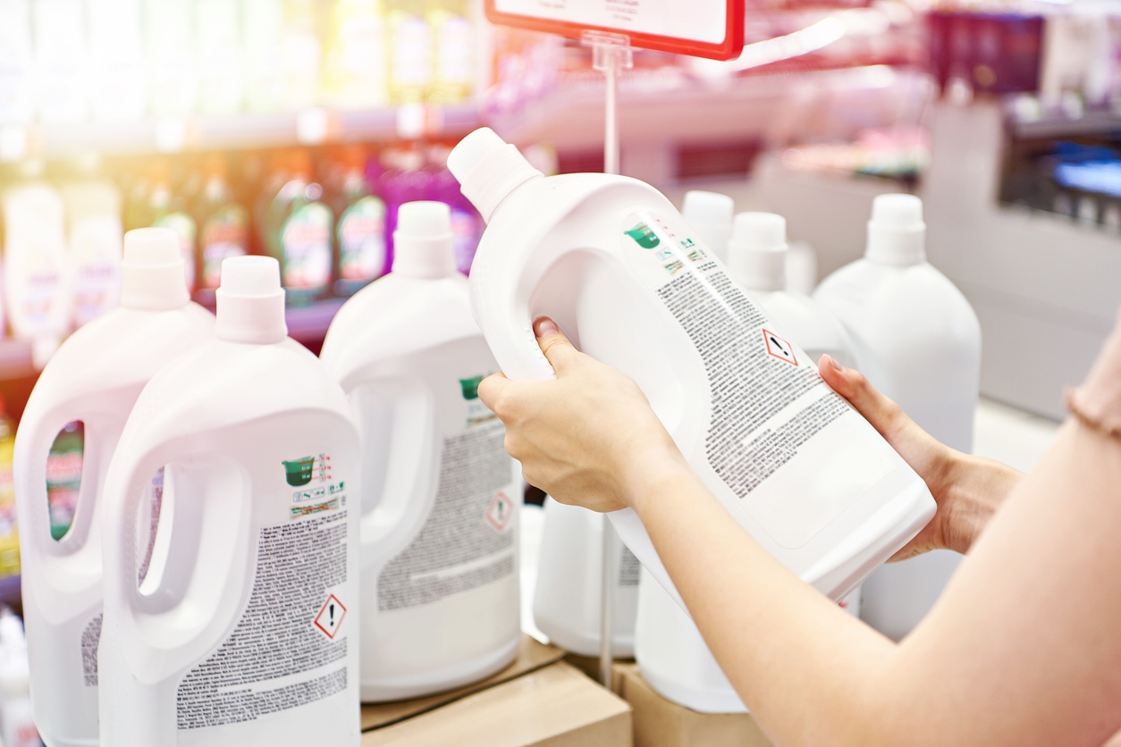 Woman holding a  laundry liquid in hand and reading the label