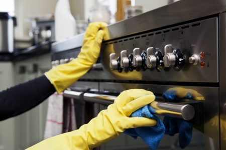 A woman cleaning stainless steel appliances using JAWS Kitchen Cleaner